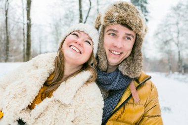 Güzel, mutlu, genç bir çift kış ormanında birbirlerine sarılıyorlar.