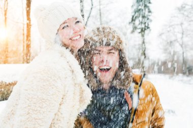Mutlu genç çift, kış ormanında birbirlerine sarılıyorlar.