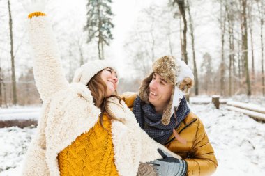 Mutlu genç çift kış ormanında birlikte eğleniyor.