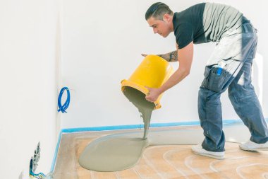 Zemin kaplaması sırasında kendi kendine yükselen çimento havanıyla çalışan işçiler. 