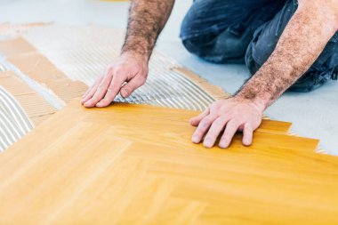 Evin tadilatı sırasında meşe parke döşemesi takan adamın kesilen görüntüsü. 