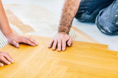 Evin tadilatı sırasında meşe parke döşeyen işçilerin kırpılmış görüntüsü  