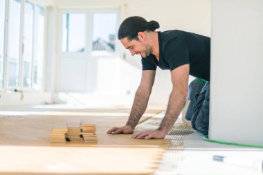 Erkek işçi ev geliştirme sırasında meşe parke döşeme  