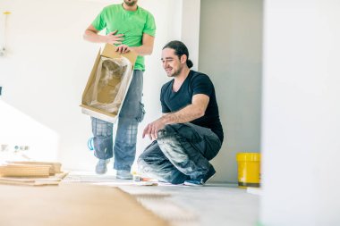 Gülümseyen işçiler ev geliştirme sırasında meşe parke döşeme  