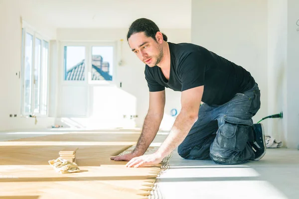 改善中にオーク寄木細工の床を設置する男性労働者 — ストック写真