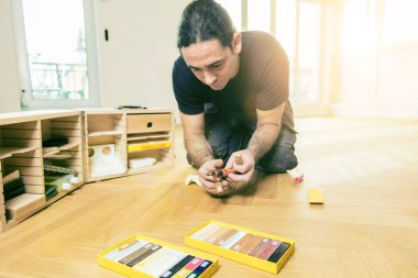 Ev tadilatı sırasında meşe parke döşemesi kuran konsantre adam  