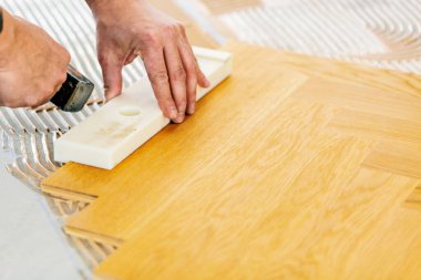 Evin tadilatı sırasında meşe parke döşemesi takan adamın kesilen görüntüsü. 