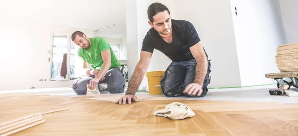 男性工人在家庭装修期间清漆橡木地板 — 图库照片