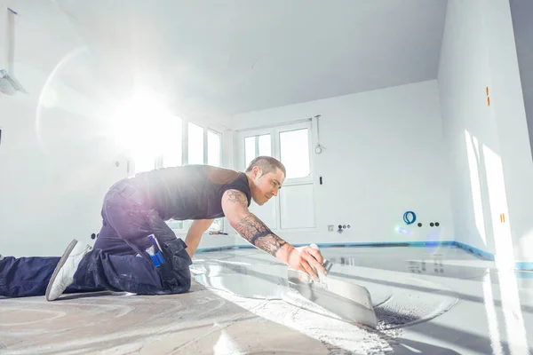自己平準化セメントモルタルで作業する床覆い中の男 — ストック写真