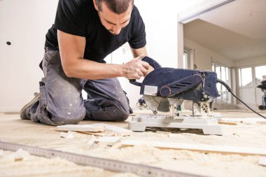 Ev tadilatı sırasında meşe parke döşemesi kuran adam  