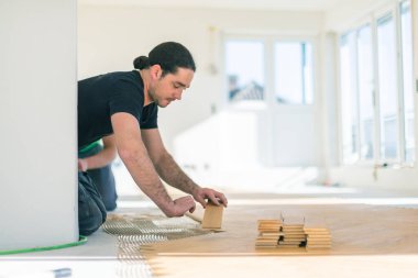 Evin tadilatı sırasında meşe parkesi döşemesini cilalayan erkek işçi