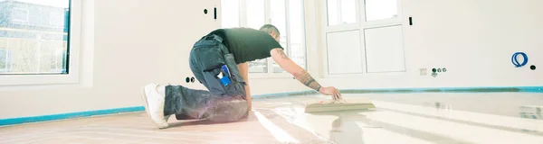 man during floor covering working with self-levelling cement mortar