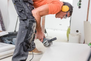 İnşaat alanında seramik fayansları kullanışlı makineyle kesen adam.