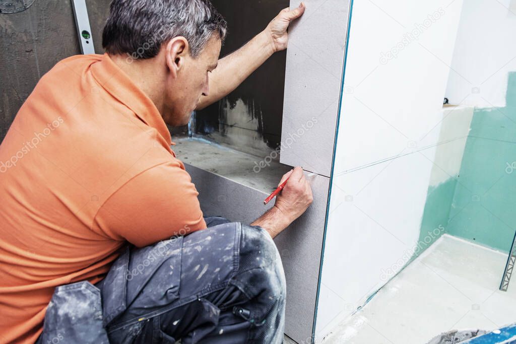 professional worker installing tiles on wall. home indoors renovation