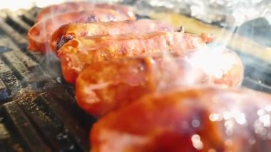 Kömür ızgarasında ızgara yapan lezzetli sosislerin yakın plan görüntüsü.