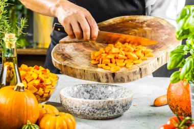 Şefin orta bölümü balkabağı çorbası için taze organik malzemeler hazırlıyor.