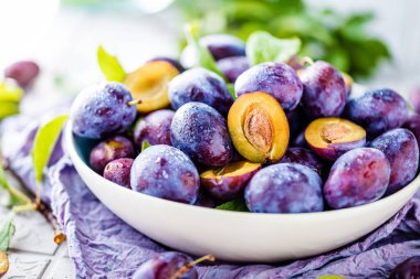 Masanın üzerinde olgun erikler olan kasenin yakın görüntüsü.