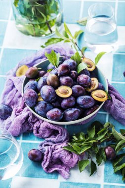 Masanın üzerinde olgun organik erikler olan kasenin yakın görüntüsü.