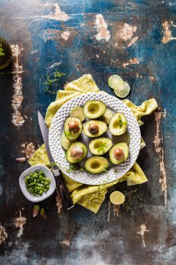 Organik yeşil avokadoların kırsal masada kızarmış ekmeklerle ikiye bölünmüş görüntüsü.