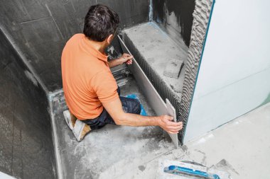 Duvara geniş format döşeyen adamın yüksek açılı görüntüsü. konut yenileme konsepti