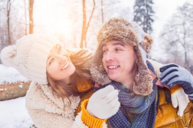 Neşeli genç çift kar yağarken sarılıyor ve birlikte eğleniyorlar.
