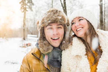 Neşeli genç çift kar yağarken sarılıyor ve birlikte eğleniyorlar.