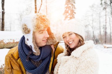 Güzel, neşeli genç çift birlikte vakit geçirip kış parkında eğleniyorlar.