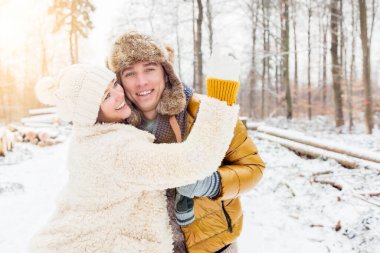 Neşeli genç çift, kış parkında sarılıp eğleniyorlar.