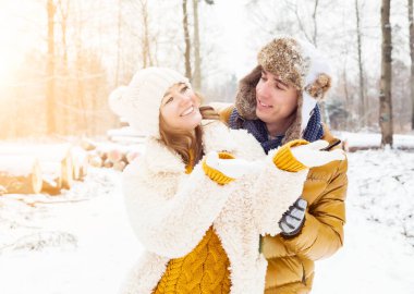 Neşeli genç çift, kış parkında sarılıp eğleniyorlar. 