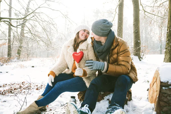 Счастливая Молодая Пара Красным Сердцем Сидя Вместе Зимнем Парке — стоковое фото