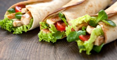 Tavuklu fajita sandviçleri ahşap masaya sarın.