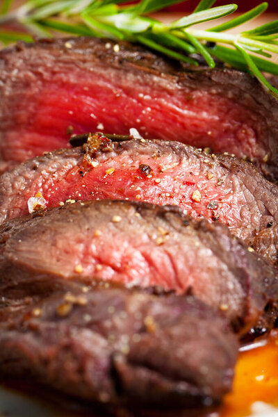 Delicious sliced grilled venison fillet on wooden table, close up