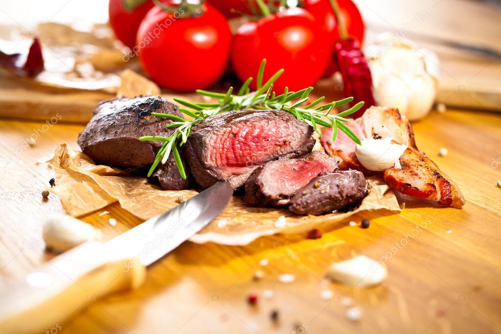 close-up view of delicious sliced grilled venison fillet with spices, herbs and vegetables