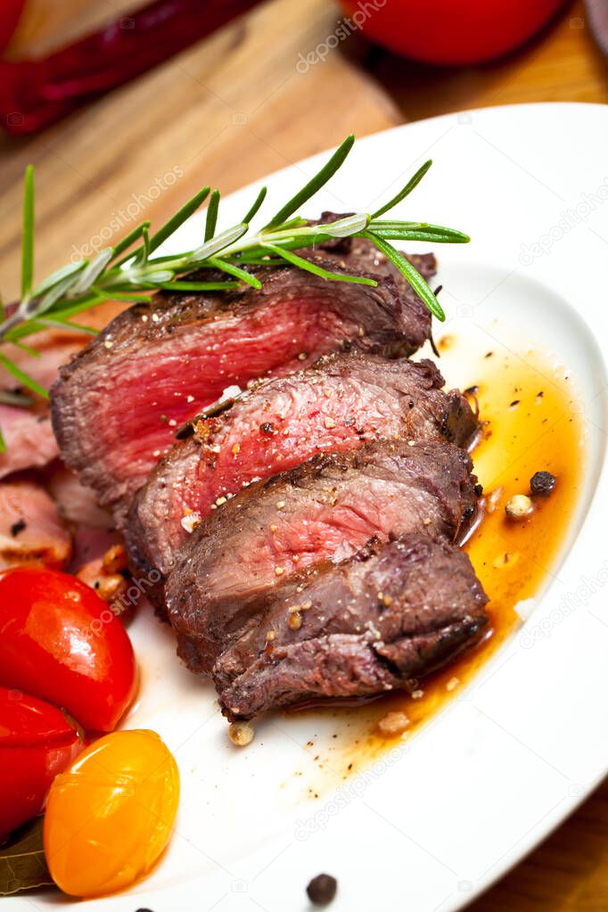 close-up view of sliced grilled venison fillet with herbs and vegetables