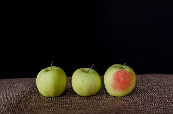 Three green apples on a black background