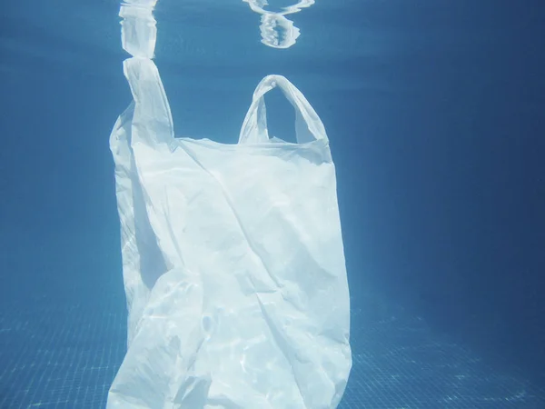 Plastic bag floating into the water. Polluted enviromental. Recycle garbage