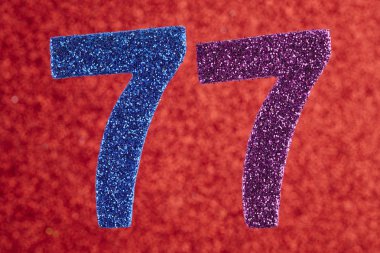 Yetmiş yedi mavi mor renk kırmızı bir arka plan üzerinde numara. Yıldönümü. Doğum günü