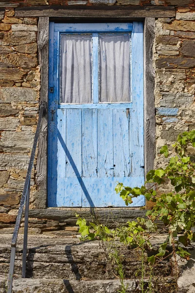 古老的锈迹斑斑的蓝色木门和石屋的立面 — 图库照片