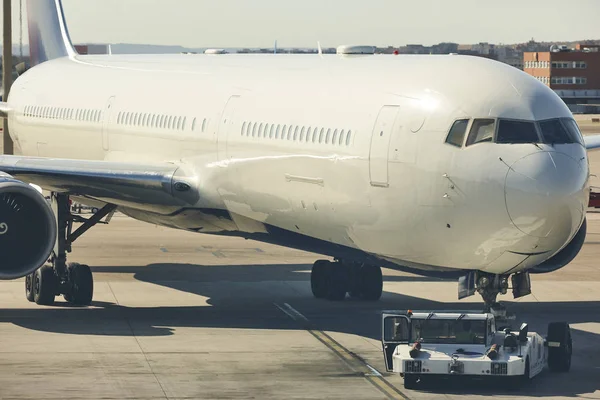 Camión bajo remolcando un avión en el aeropuerto. Transporte indu — Foto de Stock