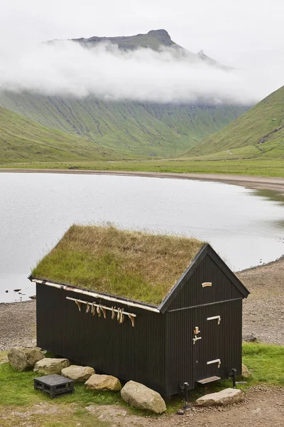 Tradizionale paesaggio delle isole Faroe con casa sul tetto in erba e lak — Foto Stock