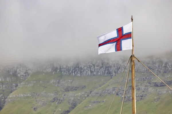 Vlajka Faerských ostrovů a symbol mávání na fjordu. — Stock fotografie