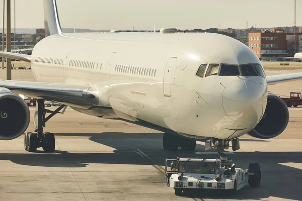 Camión bajo remolcando un avión en el aeropuerto. Transporte indu — Foto de Stock