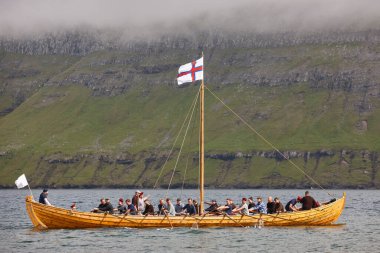 Fiyortta kürekçiler olan geleneksel bir Faroe ahşap gemisi. Faroe