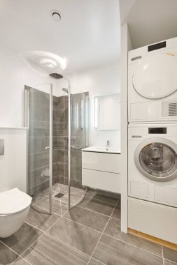 Çamaşır makinesi ve kurutma makinesiyle modern tarz banyo. Dikey