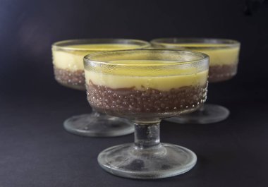 Mus, sufle, vanilya ve çikolata cam siyah, koyu arka planda puding.