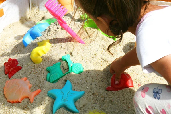 Kleines Mädchen Spielt Sandkasten Mit Buntem Spielzeug Der Sonne lizenzfreie Stockbilder