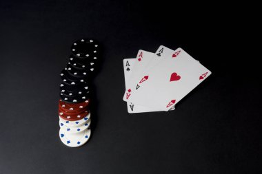 Poker kartları ve siyahta izole cips. Dört as, poker masasında.