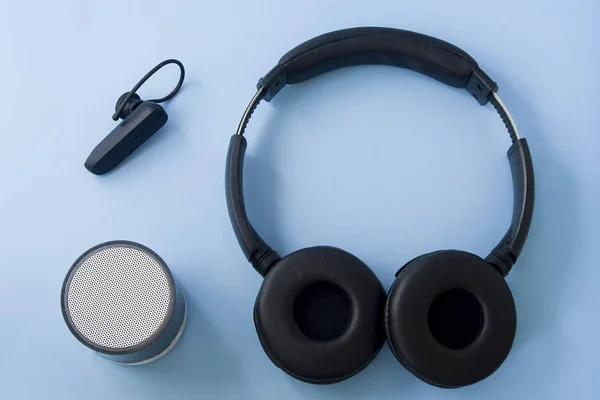 Bluetooth headset, speaker and earphone isolated on pastel blue desk. Flat lay.