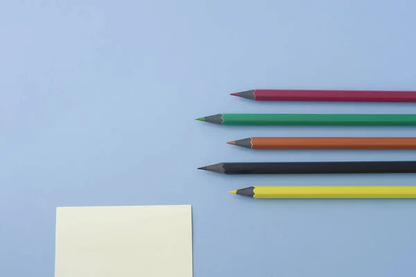 Note Avec Crayons Multicolores Isolés Sur Une Table Pastel Bleu — Photo