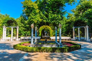 Güzel bahçe ağaçları, kemerler ve bir çocuk merkezinde bir heykeli sütunlarla çevrili.